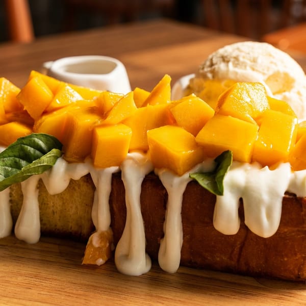 Golden toast topped with diced mango, white cream, basil leaves, and a scoop of ice cream.
